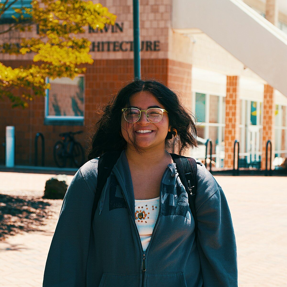 A smiling woman poses near an architecture building.